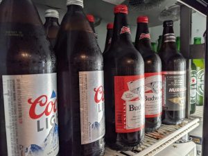 Several bottles of beer are lined up in a refrigerator.